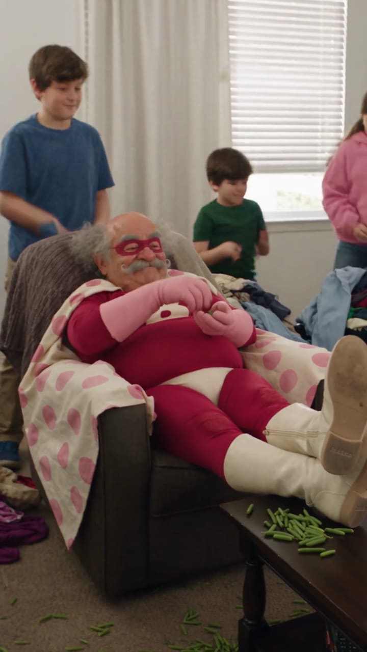 Belg lies in an armchair while the children tidy up around him.
